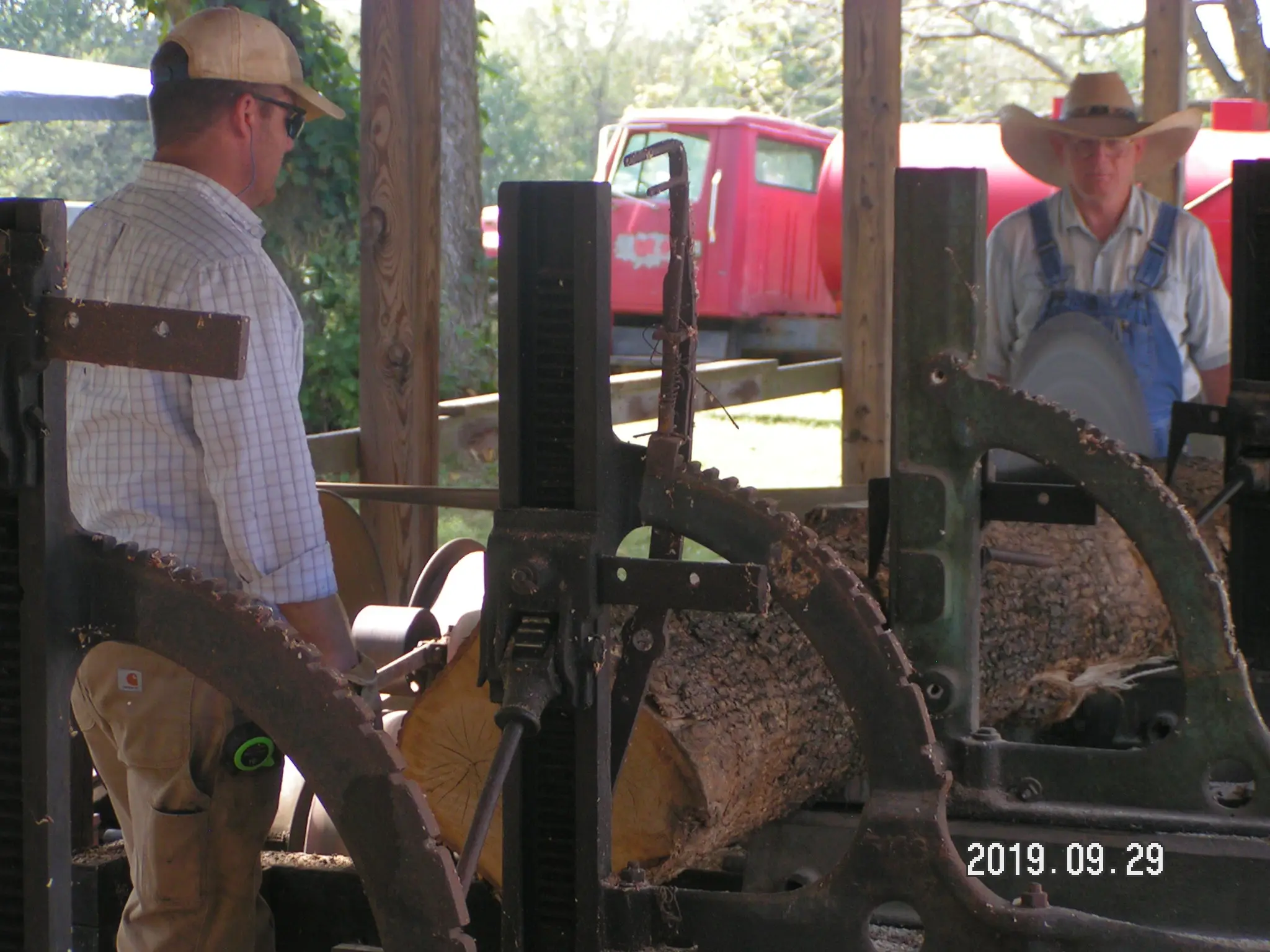There is a sawmill powered by a steam engine in operation.